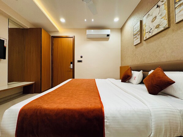 A hotel room with a bed, a wardrobe, an air conditioning unit, and artwork on the wall. - Hotel Satya Shree (Ujjain)