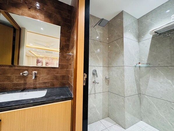 A modern bathroom with a wooden vanity, a large mirror, and a shower with a glass enclosure. - Hotel Satya Shree (Ujjain)
