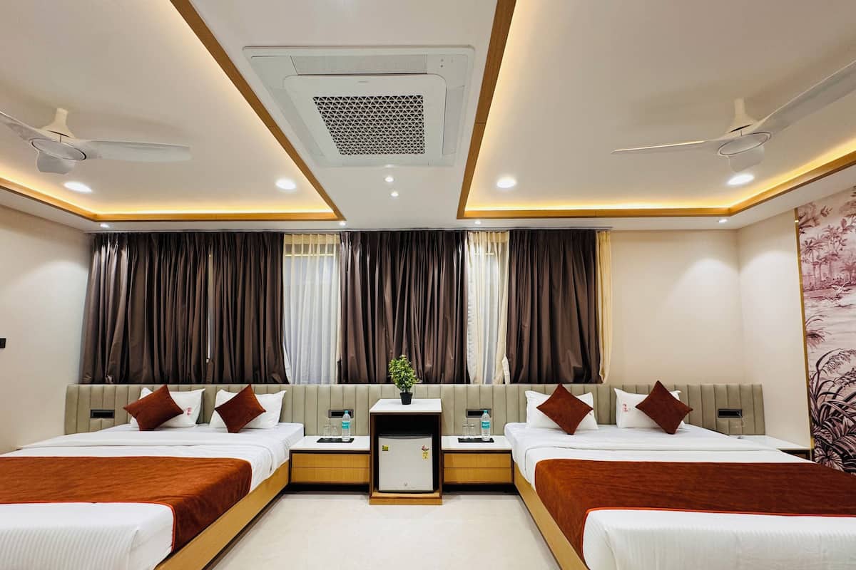 A hotel room with two beds, a small table, and a ceiling fan.