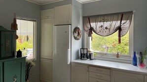 Une cuisine avec une fenêtre, un réfrigérateur, une machine à café et un meuble avec des tiroirs.