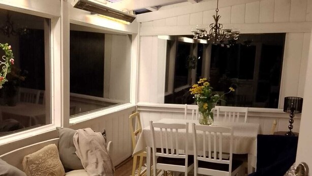 Une pièce comprenant une table à manger, des chaises, un canapé, une petite table ronde avec un saladier, et un tapis à motifs.