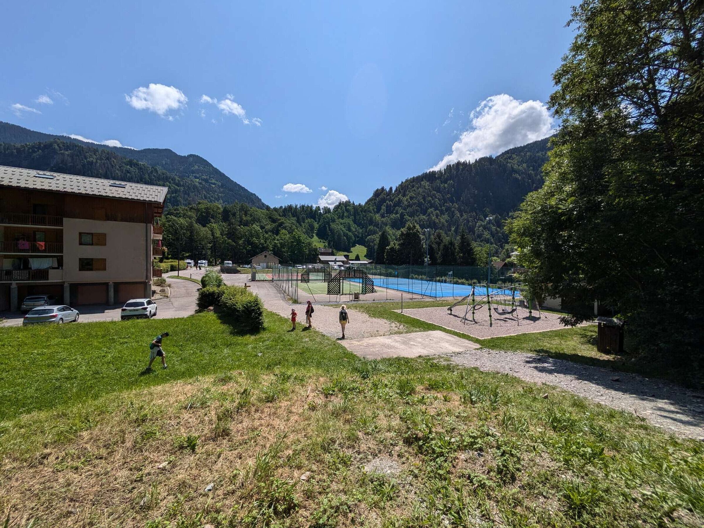 Une station de montagne dotée d’une piscine, d’un court de tennis et d’un bâtiment avec des balcons.