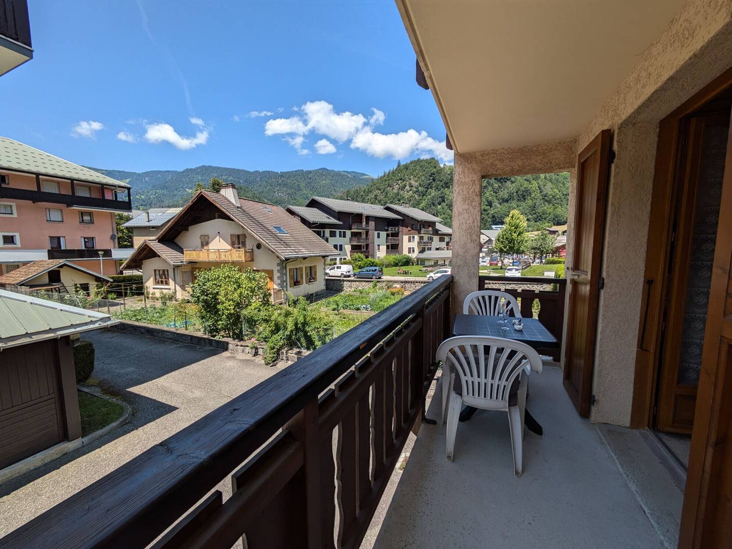 Uma varanda com mesa e cadeiras, com vista para uma área residencial com casas e montanhas.