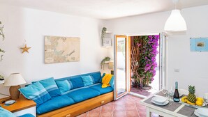 Un soggiorno luminoso con un divano blu, una mappa appesa al muro e un tavolo con un'ananas e una bottiglia.