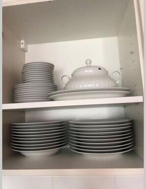 Eine Küchenschrank mit gestapelten Tellern und einem weißen Topf.