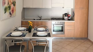 A modern kitchen with white cabinets, a dining table set for four, and a gas stove.