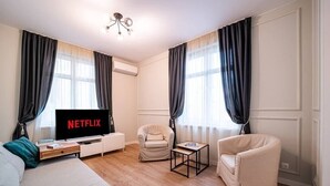 Ett modernt vardagsrum med en soffa, två fåtöljer, ett soffbord och en tv-skärm som visar ”NETFLIX”.