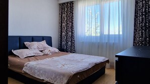 A bedroom with a bed, a dresser, and a window with curtains.
