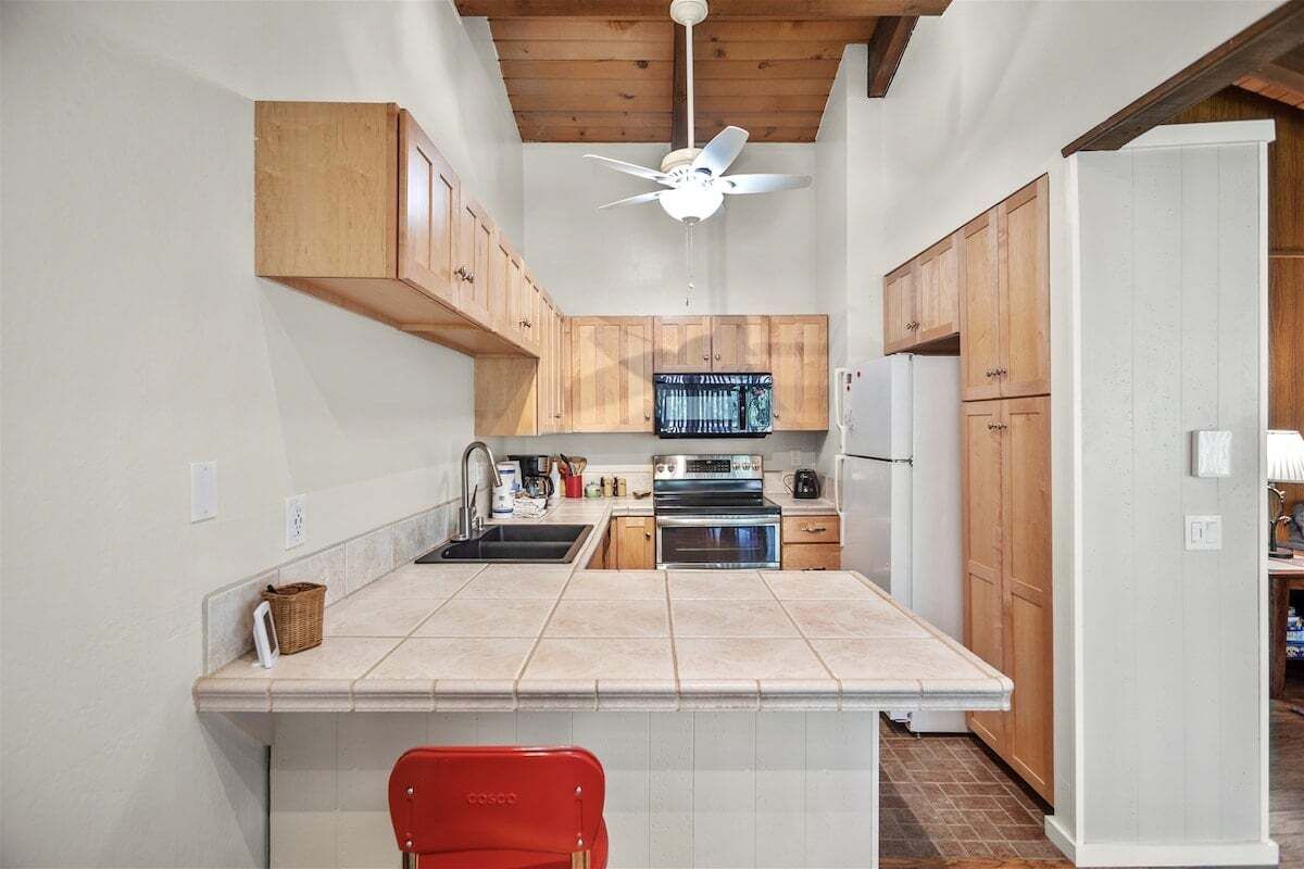 A kitchen with wooden cabinets, a central island, a ceiling fan, and a refrigerator.