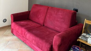 Un canapé rouge dans une pièce dont le mur est gris et qui est orné d’une bande jaune.