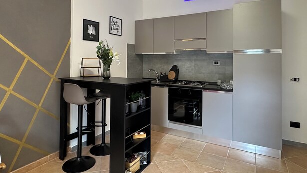 Une cuisine moderne avec un bar noir, des meubles gris et un four encastré.