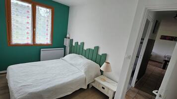 A bedroom with a bed, a nightstand, a window with blinds, and a green headboard.