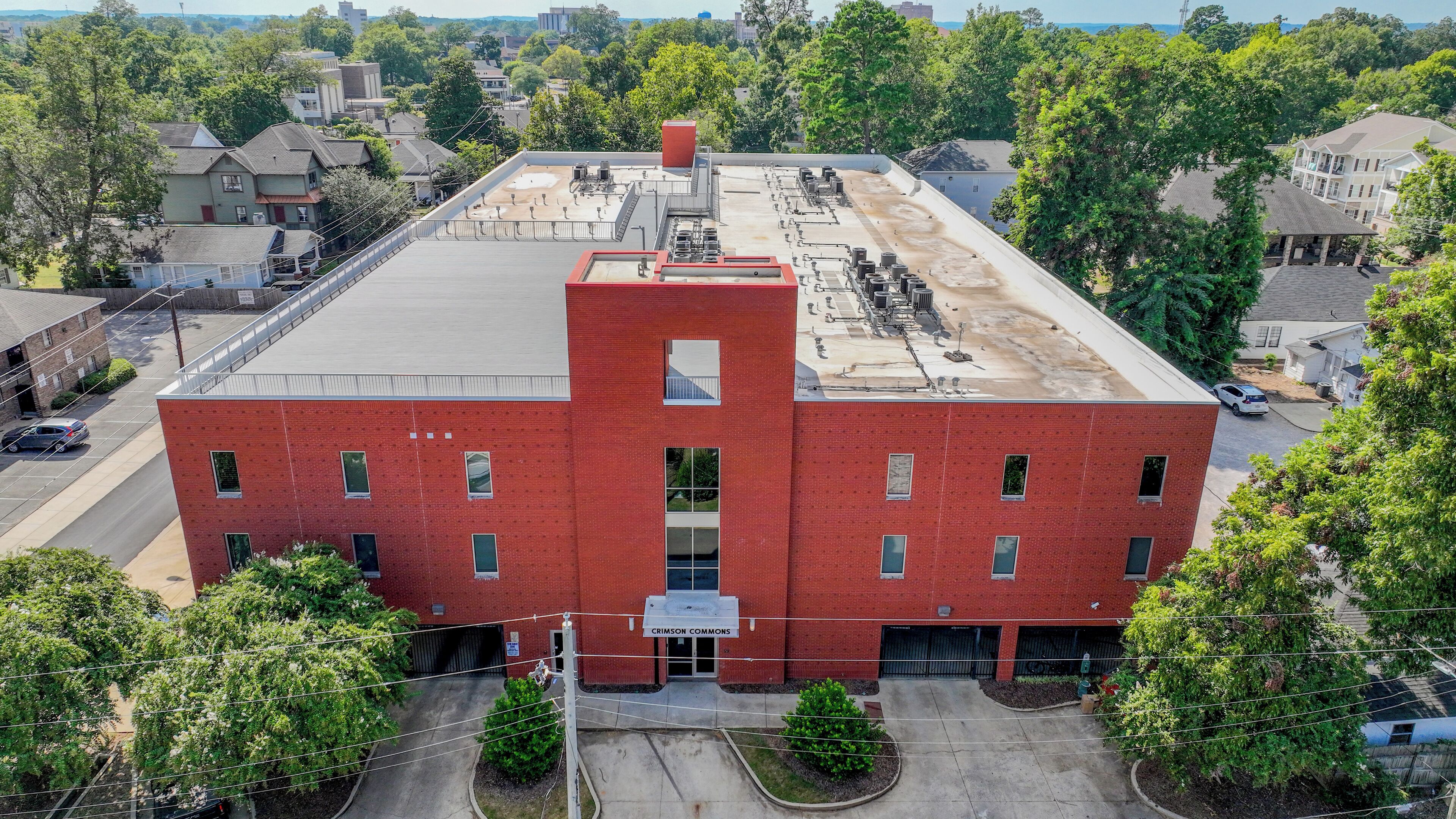 A red brick building with a flat roof, multiple windows, and a central entrance.