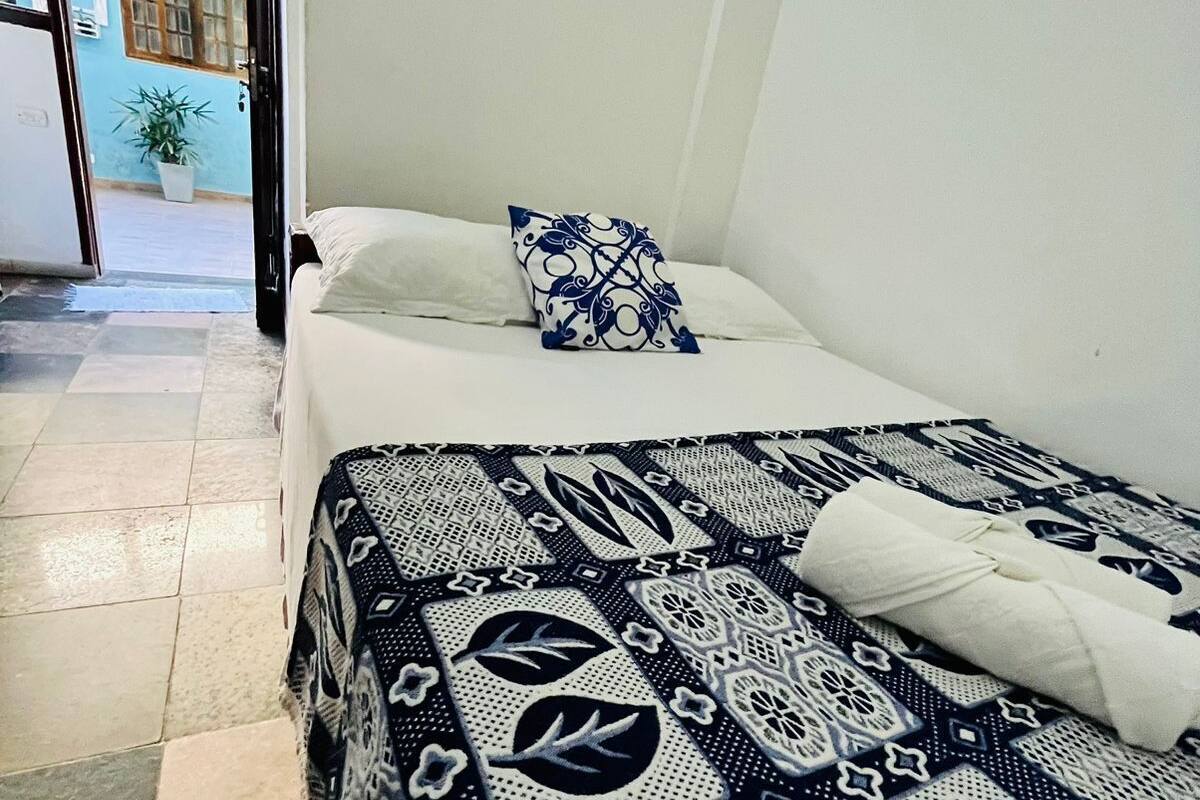 Une chambre d’hôtel avec un lit, un oreiller et une couvre-lit à motifs.