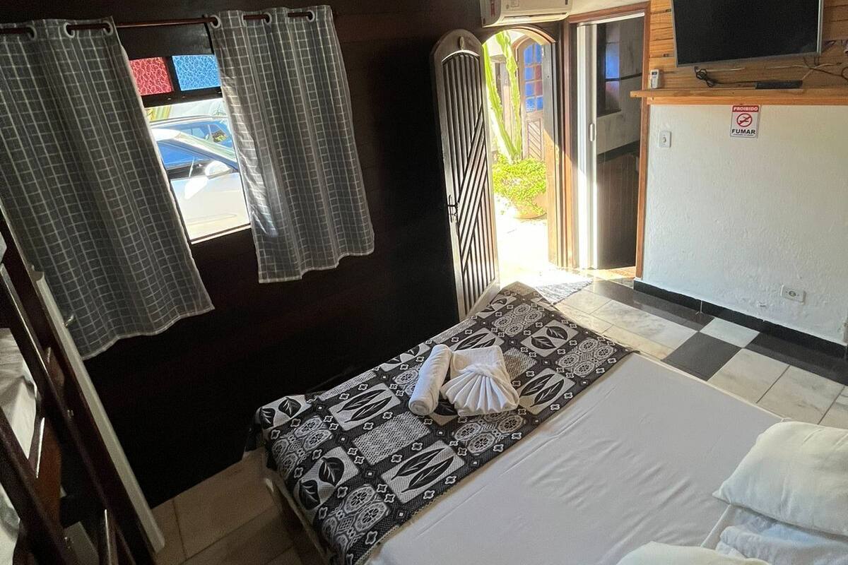 Une chambre à coucher avec un lit, un ventilateur de plafond, une télévision et une fenêtre avec des rideaux.