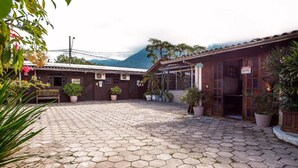 A courtyard with hexagonal paving, a wooden bench, and potted plants. - Pousada Novo Encanto Maresias (São Sebastião)
