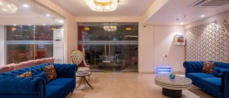 A modern hotel lobby with blue sofas, a round coffee table, and a chandelier.