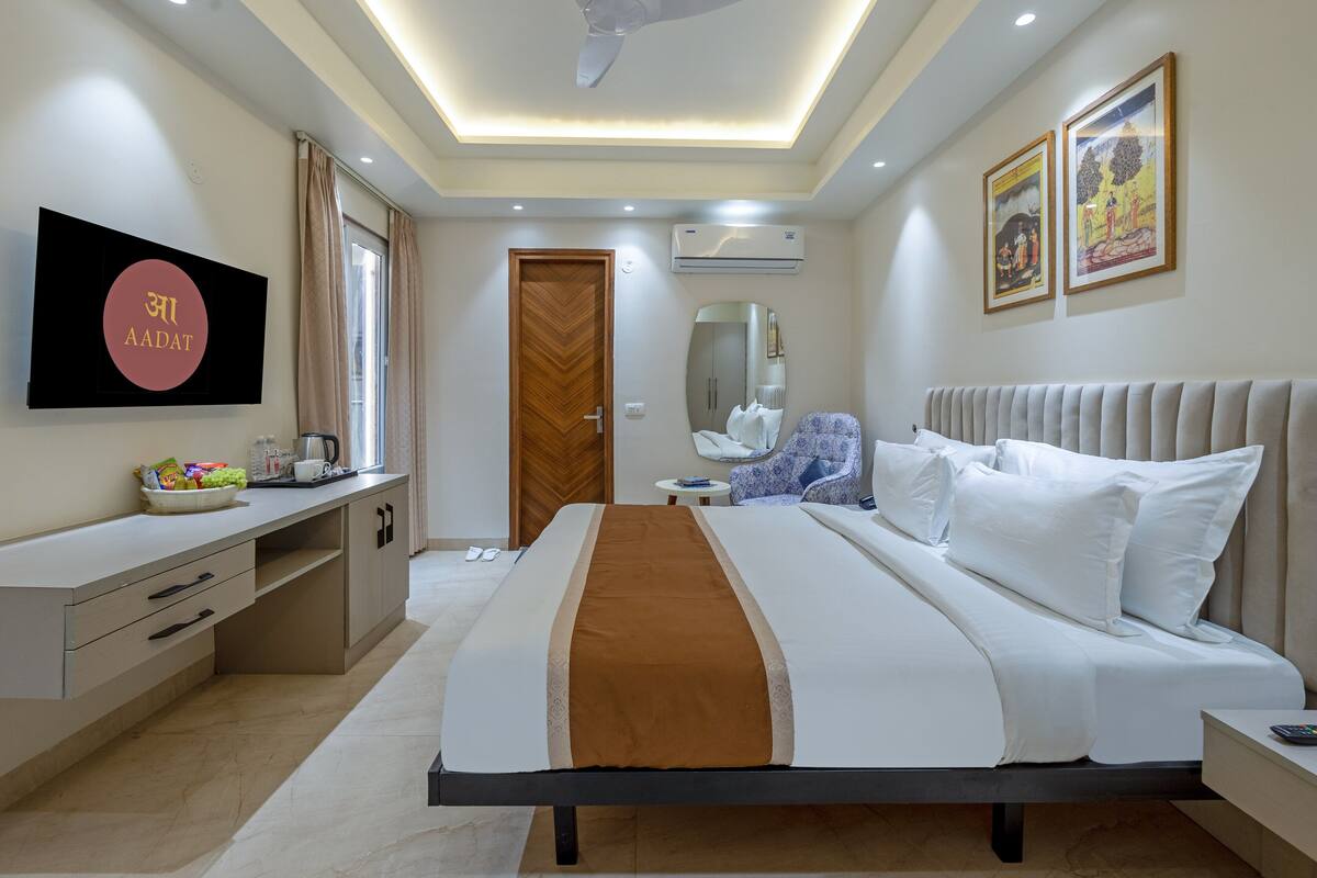 A modern hotel room with a large bed, a desk, a wardrobe, and a television.