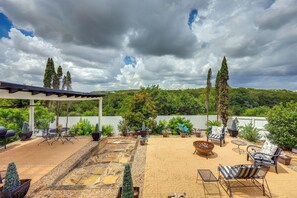 Un espacio de patio cubierto con mobiliario exterior, un brasero y una variedad de plantas en macetas.