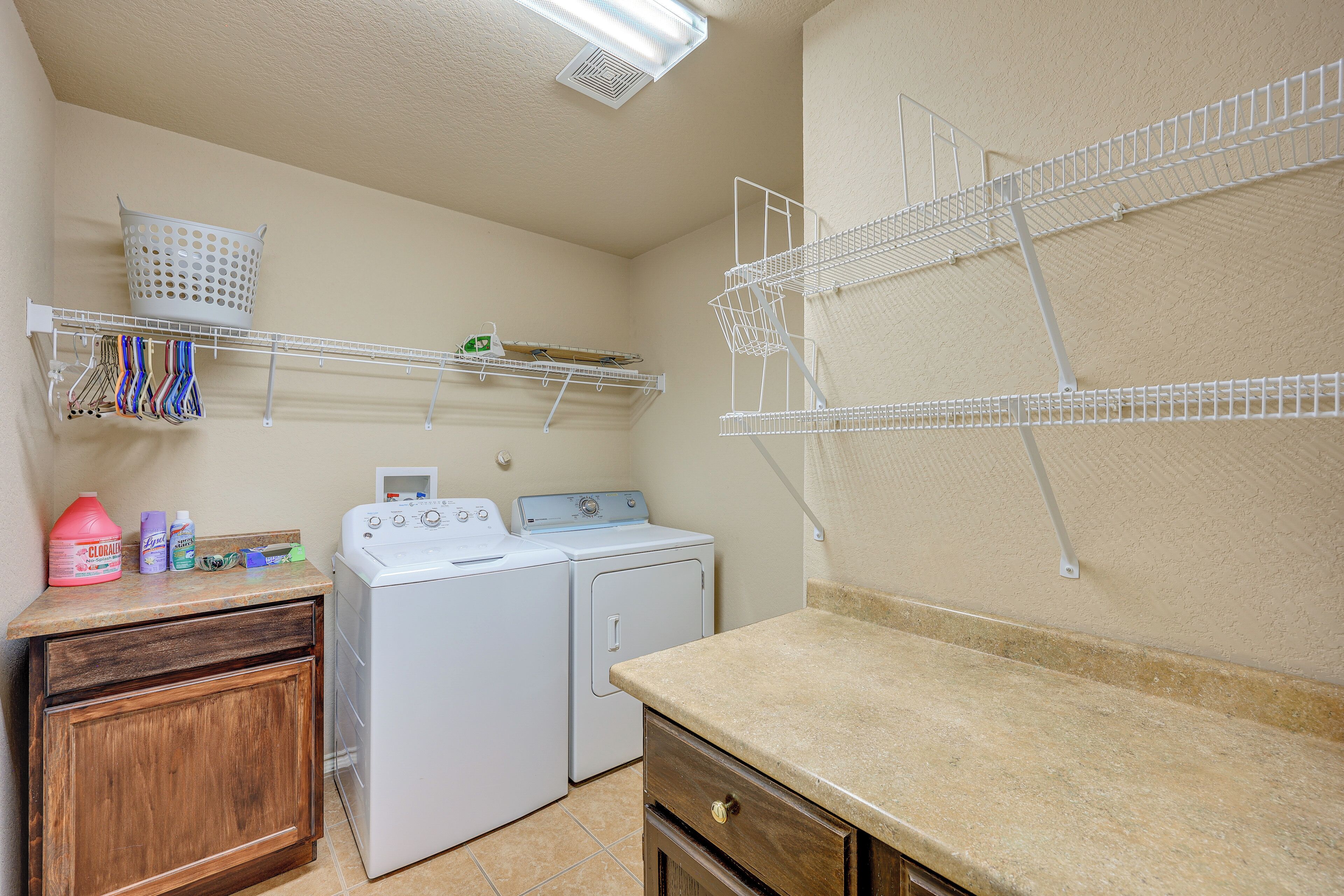 A laundry area with a washing machine, dryer, and shelves for hanging clothes.
