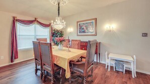 A dining room with a wooden table, chairs, a chandelier, and a painting on the wall. - San Antonio Home - Outdoor Oasis & Greenbelt Views (San Antonio)