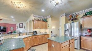 A kitchen with wooden cabinets, a stainless steel refrigerator, and a granite countertop. - San Antonio Home - Outdoor Oasis & Greenbelt Views (San Antonio)