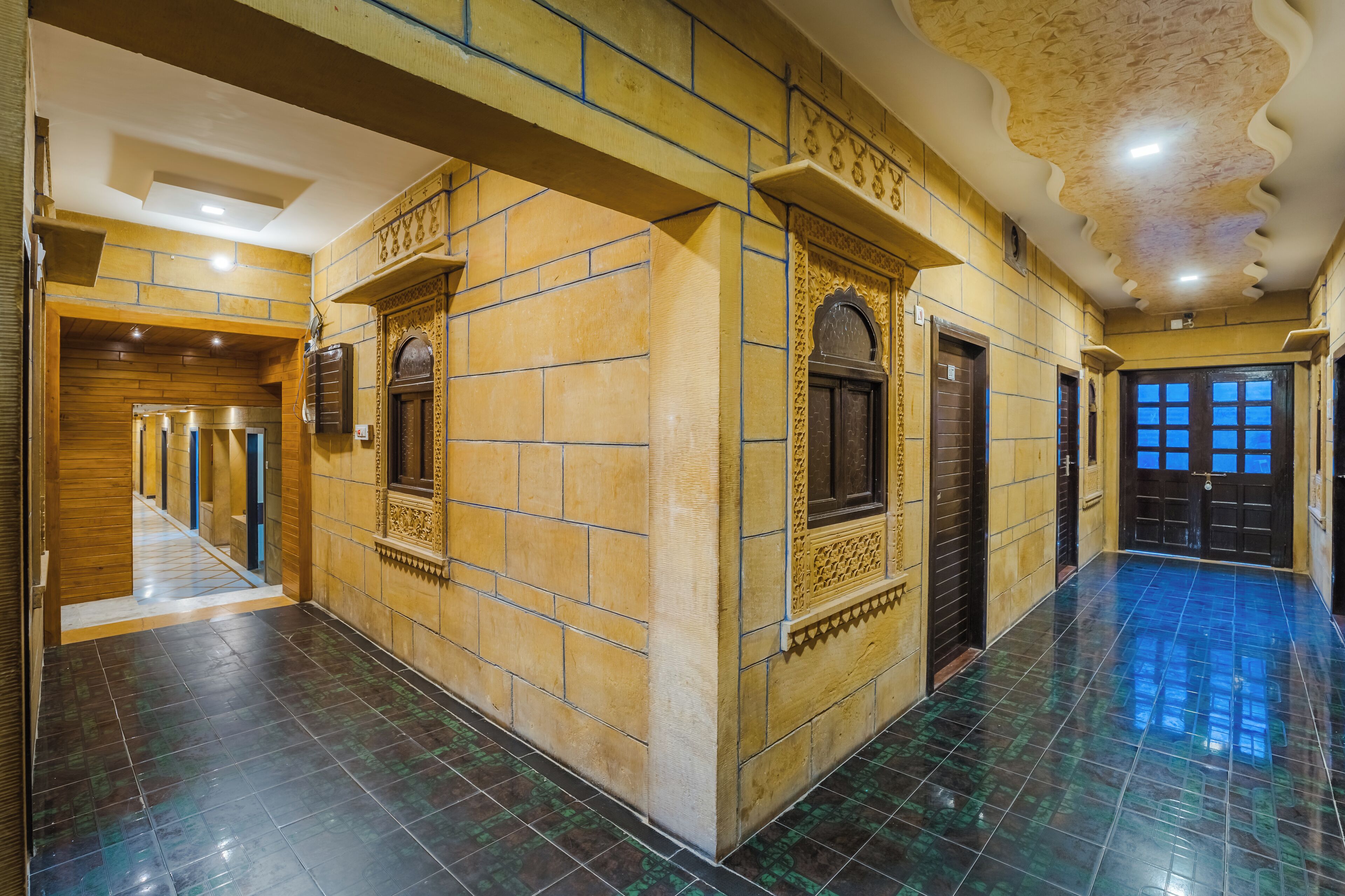 A corridor with tiled walls and floor, featuring a series of doors and a staircase.