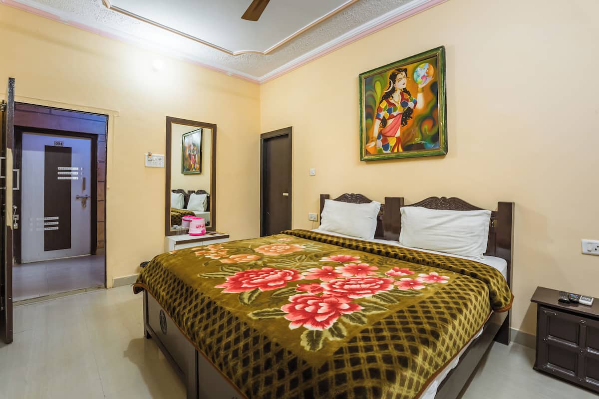 A hotel room with a bed, a nightstand, a painting, and a door.