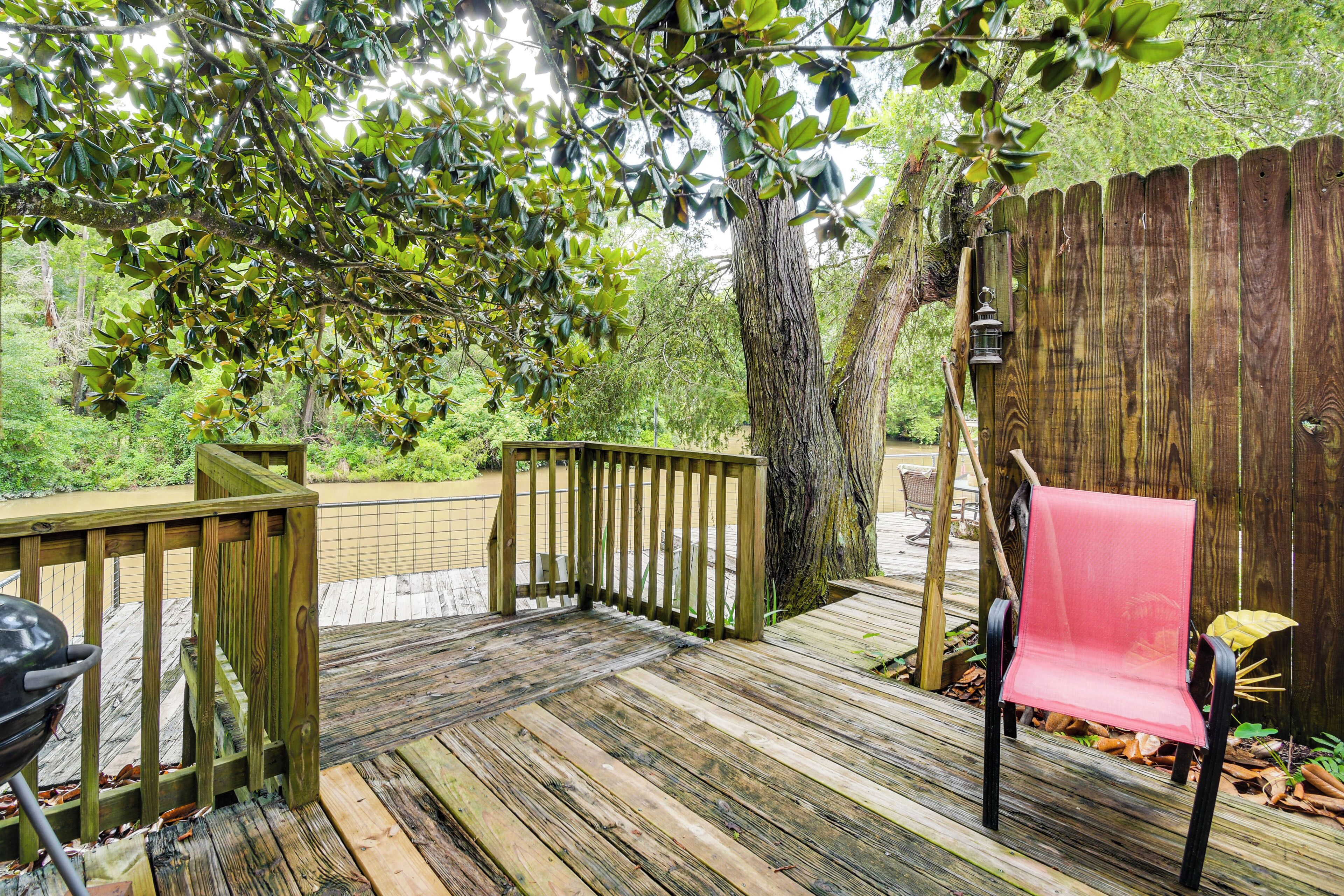 A wooden deck with a red chair, a grill, and a lantern.