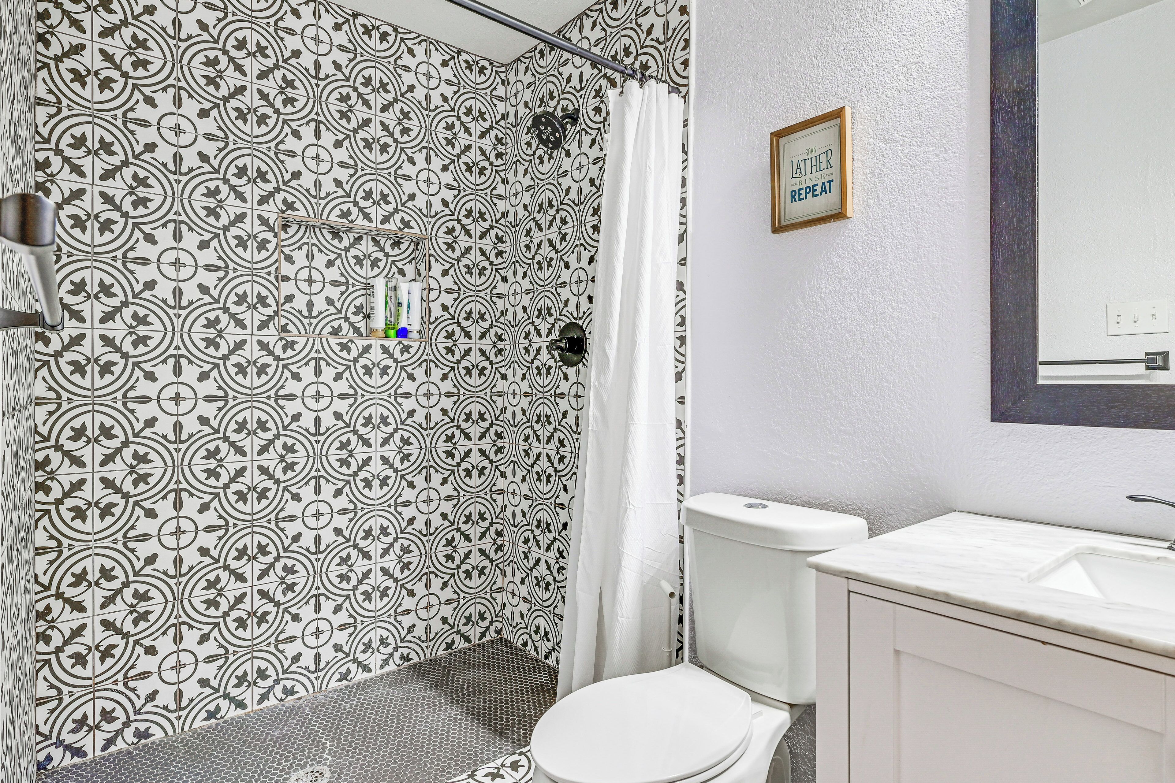 A bathroom with patterned tiles, a toilet, a sink, and a shower curtain.