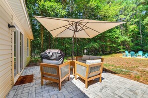 A patio with two wicker chairs and a large umbrella, surrounded by a brick floor and a wooden deck. - Mooresville Retreat w/ Patio, 1 Mi to Lake Norman! (Mooresville)