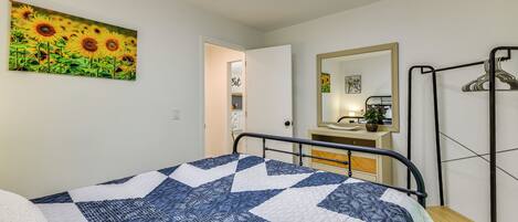 Un dormitorio con una cama, un espejo y un cuadro de girasoles.