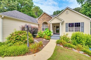 A two-story house with a stone facade, a front porch, and a landscaped garden. - Game Room & Peaceful Deck: Dacula Family Home (Dacula)