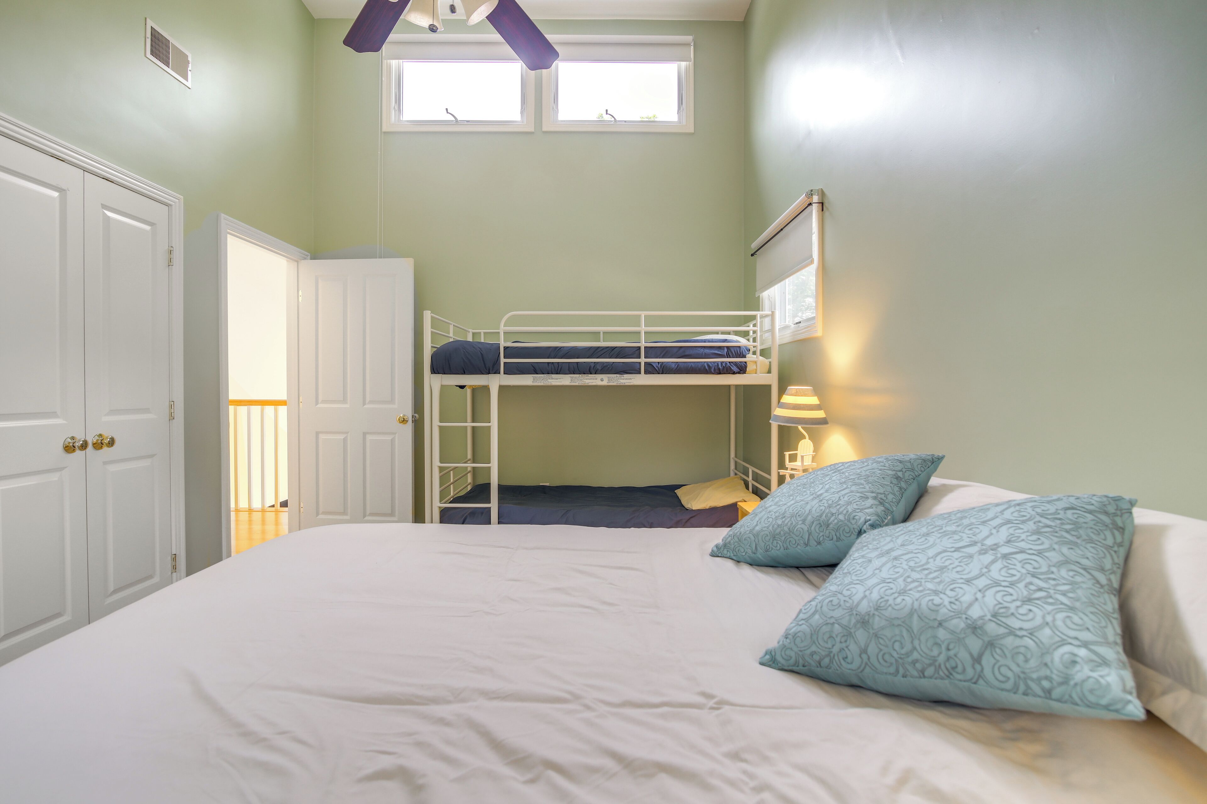 Une pièce avec un lit superposé, un grand lit, une porte et une fenêtre.