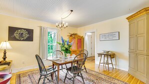 A dining room with a wooden table, chairs, a chandelier, and a floral arrangement. - Idyllic Vermont Farmhouse: Mtn Views on 200 Acres! (Groton)