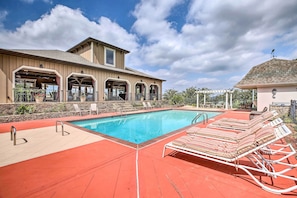 Una piscina con sillones de descanso y una zona cubierta con pérgola.