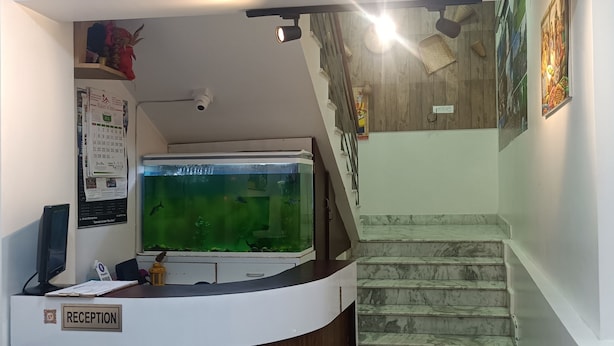 A reception area with a reception desk, a large aquarium, and a staircase. - HOTEL SHILLONG RAINS INN BY ROH (Shillong)