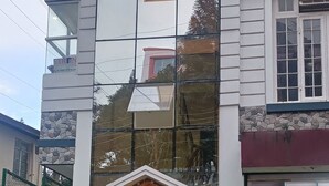 A building with a glass facade reflecting the surroundings. - HOTEL SHILLONG RAINS INN BY ROH (Shillong)