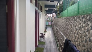 A corridor with a stone wall on one side and a metal railing on the other. There are potted plants along the corridor. - HOTEL SHILLONG RAINS INN BY ROH (Shillong)
