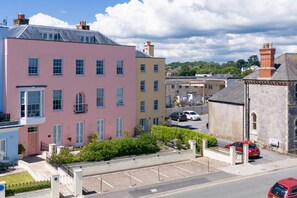 A pink building with a flat roof and multiple windows. - Nash House - Seafront With Parking Close to Town (Tenby)