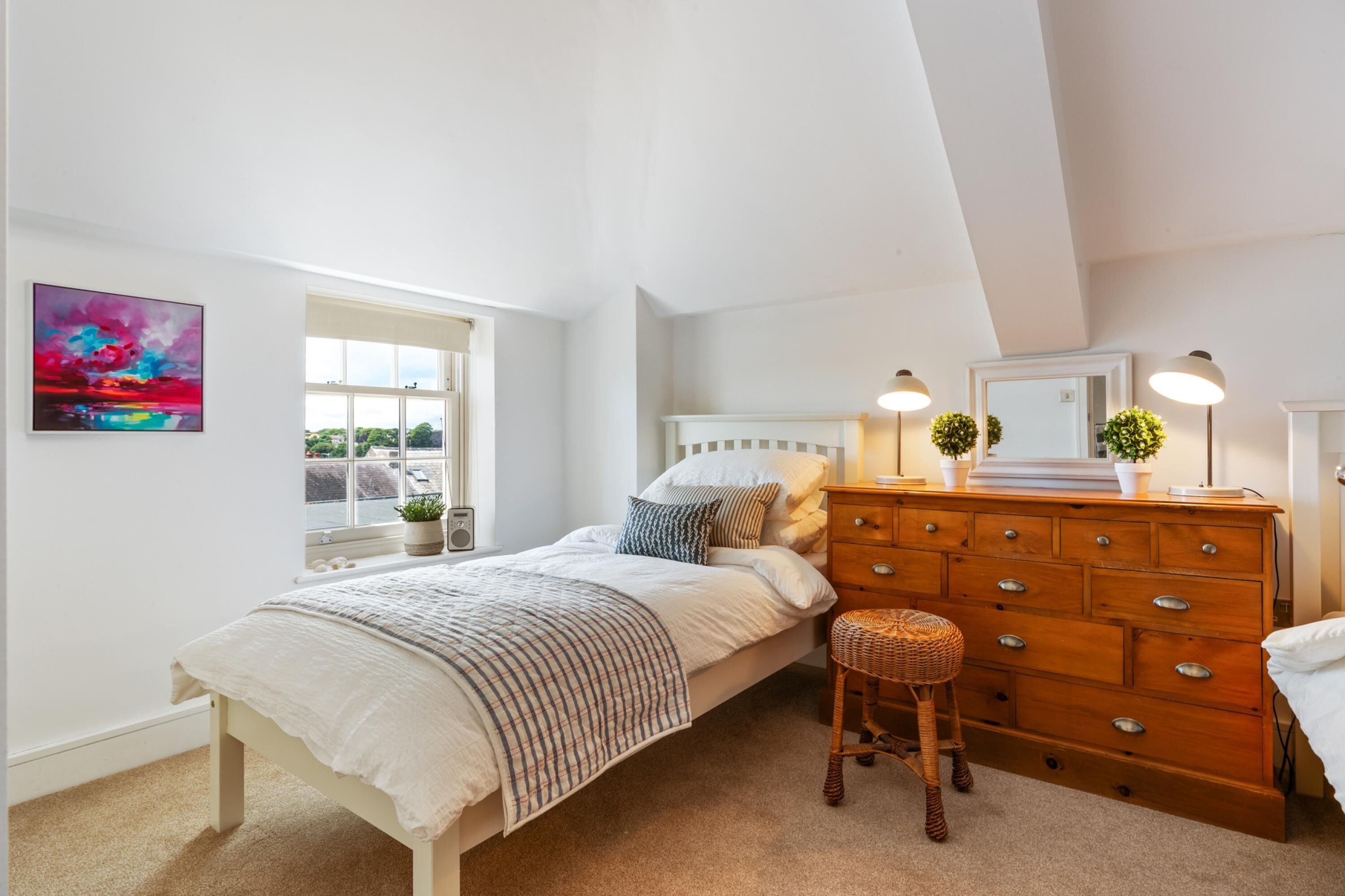 Une chambre à coucher avec un lit, une commode et une fenêtre.