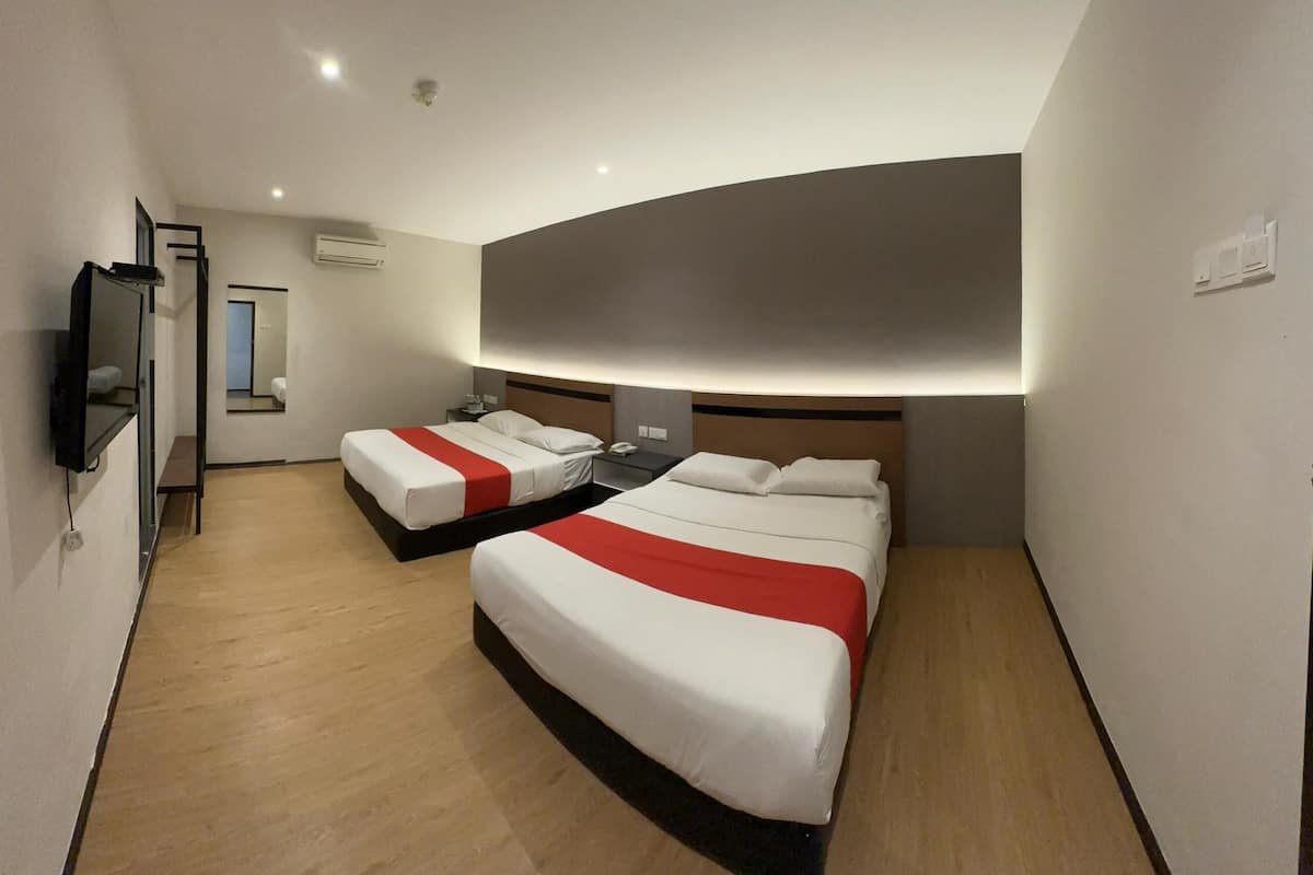 Ein Hotelzimmer mit zwei Betten, einem Fernseher und einem Spiegel.