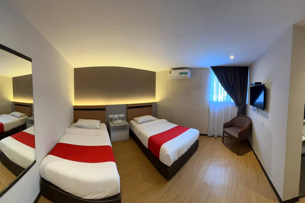 Ein Hotelzimmer mit drei Betten, einem Fernseher und einem Spiegel.