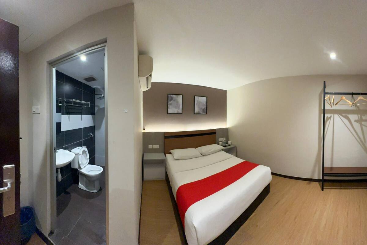 Ein Hotelzimmer mit Bett, Fernseher, Badezimmer mit Toilette und Waschbecken sowie einer Duschkabine.