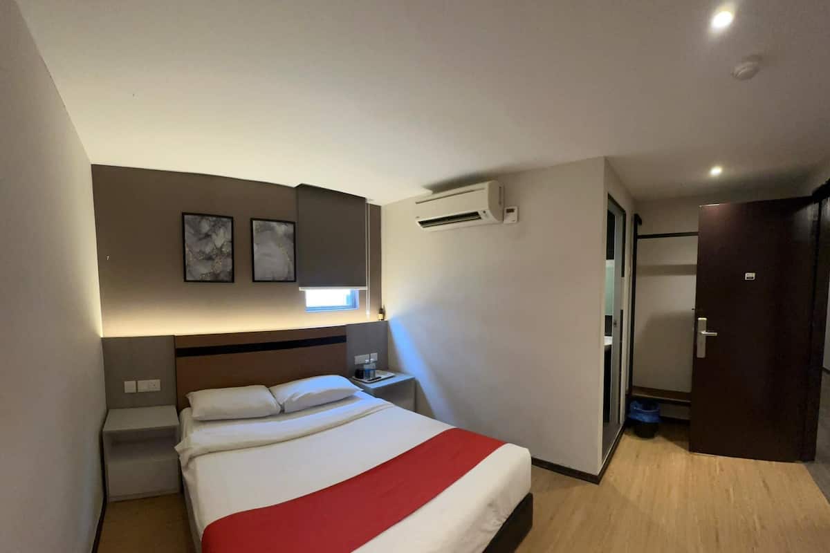 Ein modernes Hotelzimmer mit einem großen Bett, einem Nachttisch, einer Klimaanlage und einer Tür zu einem Badezimmer.