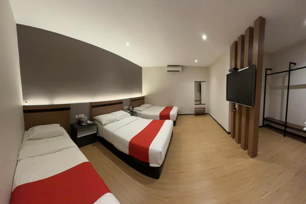 Ein Hotelzimmer mit drei Betten, einem Flachbildfernseher, einem Spiegel und Holzboden.