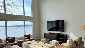 A spacious living room with a large sectional sofa, a flat-screen TV, and a ceiling fan. - Spacious House + boat house on clear, sandy-bottom lake. Arcade + Billiards room (Wolcottville)