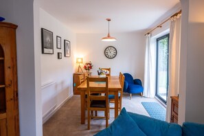 Un coin repas avec une table et des chaises en bois, une horloge au mur et un canapé bleu.