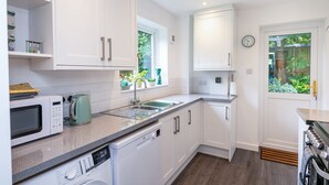 A modern kitchen with white cabinetry, a built-in dishwasher, a microwave, and a sink. - Hawthorn View: Bristol Large House STAE-Homes (Bradley Stoke)