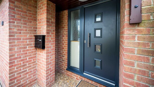 A black door with a mail slot, a window, and a mailbox on the brick wall. - Hawthorn View: Bristol Large House STAE-Homes (Bradley Stoke)